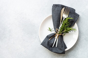 Table setting on white. White plate, cutlery and napkin with rosemary. Flat lay image with copy...