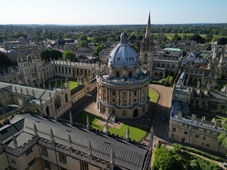 Bodleian Library Oxford, wide drone shot of the famous Oxford University colleges on a quiet summer morning. Dreaming spires, quadrangle and blue skies with fields in the distance.