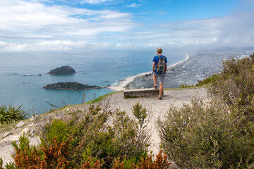 Obraz premium Young man looking out across Tauranga coastline from Mt. Maunganui - Tauranga, New Zealand