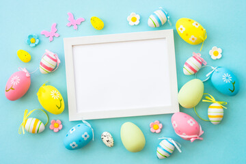 Easter background on blue. Colored easter eggs with decorations and white frame for text. Flat lay...