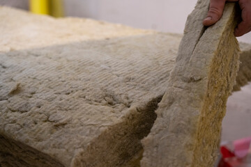 Hands Expertly Cutting Mineral Wool with a Specialized Knife.