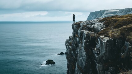 Person stood on a cliff overlooking the sea