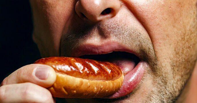 Close up of man eating hot dog with his tongue out.