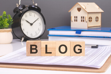 blog word in wooden blocks with small wooden house and alarm clock on gray background. timely and...