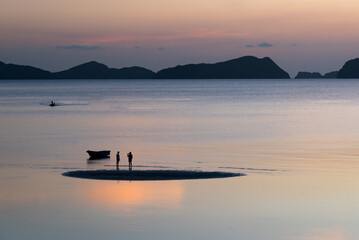 couple en attente sur une plage au coucher du soleil