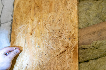 Meticulous Craftsman Prepares, Holding Screw to Affix OSB Plate with Expert Precision.