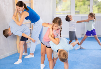 In training hall, children are working on arm twists, learning to control and subdue opponents.
