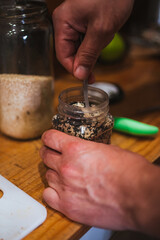 Man mixing black and white sesame seeds inside of a recipient. They are used to be put on toasts.