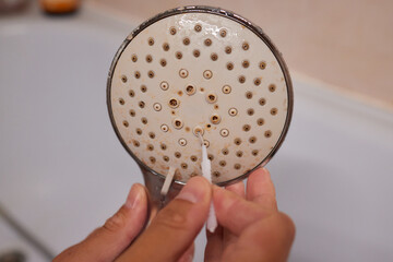 Detail cropped shot of unrecognizable man in protective gloves cleaning calcified shower head using...
