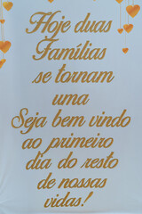 A white sign with gold letters written: "Today two families become one, welcome to the first day of the rest of our lives"