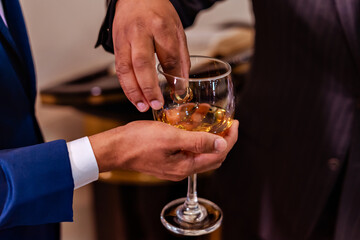 the groom's hands holding a cup of oil as the rings are anointed