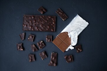 Sweet temptation: two chocolate bars on a dark background.  Flat lay, top view.  A combination of milk and dark chocolate.