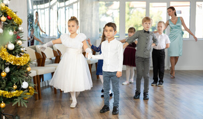 Elegantly dressed children, preteen girls and boys performing curtsy and bow during festive dance...