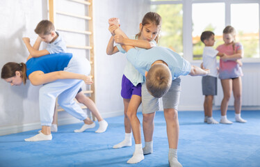 Obraz na płótnie Canvas In training hall, children are working on arm twists, learning to control and subdue opponents.