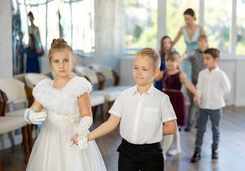 Active preteen children practicing ballroom dances in pairs during dancing classes