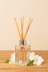 Reed aroma diffuser with freesia flower on wooden table