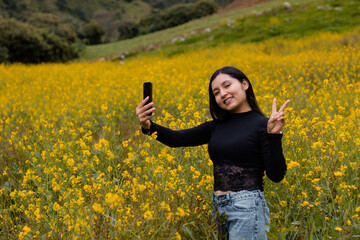 Naklejka na ściany i meble Contrastes florales entre la serenidad de las flores amarillas y la modernidad de un turista alegre con camiseta negra y su celular,comunicación aire libre,tecnologia,estilo de vida