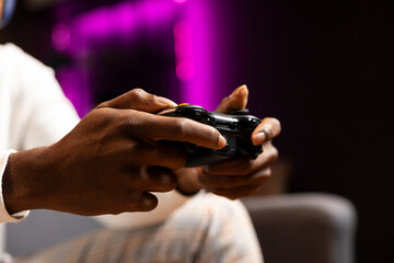 Close up shot of controller hold by gamer at home gaming and enjoying leisure time. African...