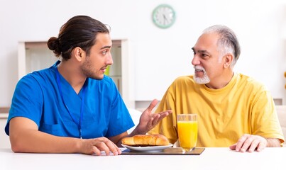 Young male doctor visiting old patient at home