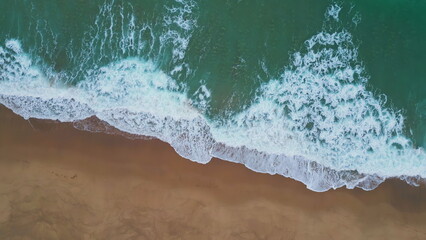 White marine foam washing sand closeup. Aerial turquoise water rolling seashore