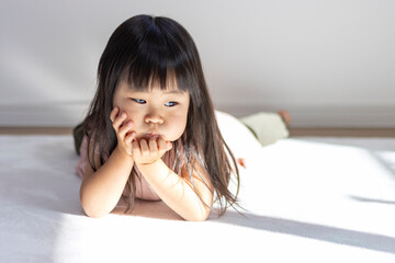 寝転がる不機嫌な女の子の様子（3歳、日本人） - obrazy, fototapety, plakaty