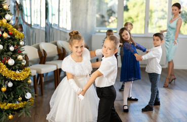 Christmas ball - group of preteen children in festive clothes dances a foxtrot near the New Year...