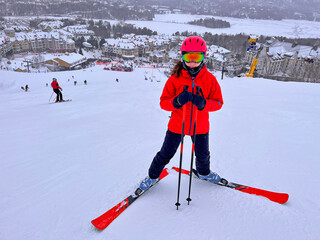 Colorful teenager skier in front of Mont Tremblant resort during the winter, Quebec, Canada