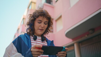 Girl playing portable console walking street closeup. Teen involved video game