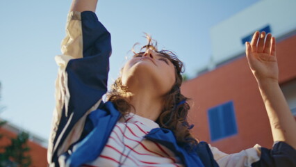 Naklejka premium Girl headphones dancing sunlight raising hands up closeup. Woman listening music