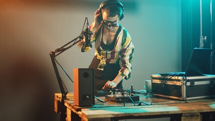 Female performer using mixing turntables and buttons to play remixed songs at party, having fun...