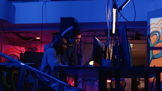 African american experienced hacker in secret hideaway teaching new member how to steal valuable data by taking advantage of security breaches, learning how to gain unauthorized access to systems