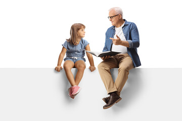 Obraz premium Mature man holding a book and talking to a little girl