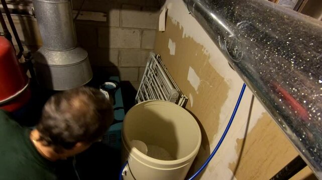 woman adding up a bag of salt in house water softener container