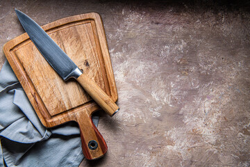 wooden cutting board, knife and napkin on the kitchen table. Space for text.