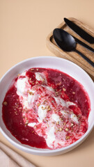 A plate of cheese fritters in cream-cherry sauce top view, flat lay on beige background