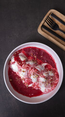 A plate of cheese fritters in cream-cherry sauce top view, flat lay on dark background