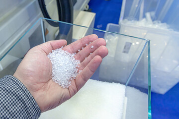 Polypropylene granules in a man's hand, against the background of production equipment for the...