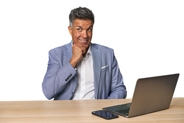 Elegant businessman at desk with laptop relaxed thinking about something looking at a copy space.