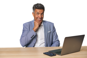 Elegant businessman at desk with laptop relaxed thinking about something looking at a copy space.