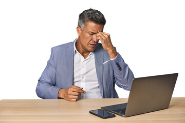 Elegant businessman at desk with laptop having a head ache, touching front of the face.