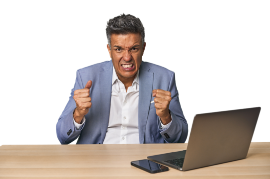 Elegant businessman at desk with laptop upset screaming with tense hands.