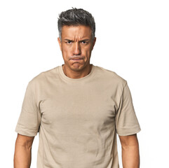 Fototapeta premium Middle-aged Latino man blows cheeks, has tired expression. Facial expression concept.