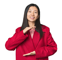 Young Chinese woman in studio setting holding something with both hands, product presentation.