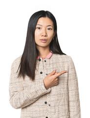 Young Chinese woman in studio setting pointing to the side