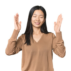 Young Chinese woman in studio setting joyful laughing a lot. Happiness concept.