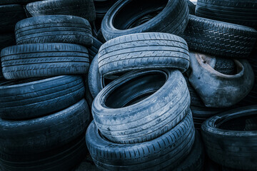 Pile of car tires in cool blue tones: many old tires of different sizes and profiles stacked...