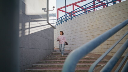Girl skater walking stairs down city holding longboard. Woman listening music