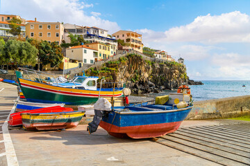 Colorful small fishing boats of blue, yellow and red line the small marina harbor at the small...