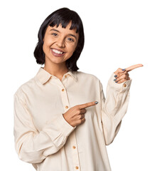 Young Hispanic woman with short black hair in studio excited pointing with forefingers away.