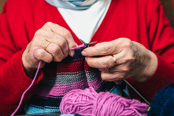 closeup horizontal photo of senior woman hands sewing with wool and needles